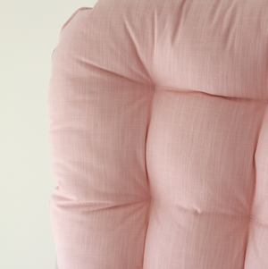 Close-up of a pink glider rocker replacement cushion with a soft texture on a light background